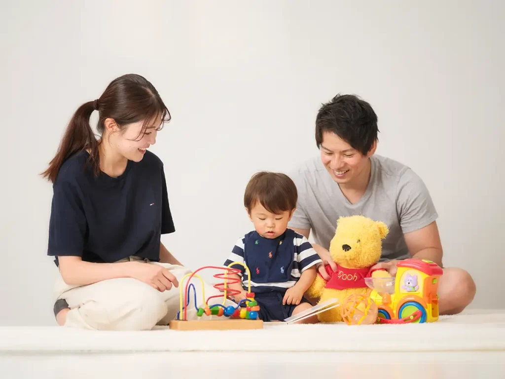 絵本を夢中で読むこどもを笑顔で眺める両親